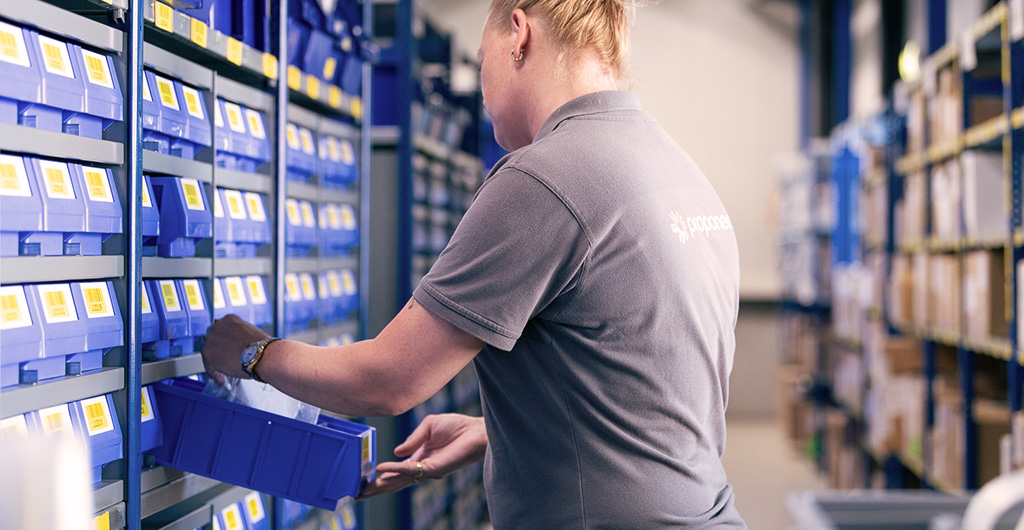 Man in warehouse shelving, pulling out a blue container with product parts