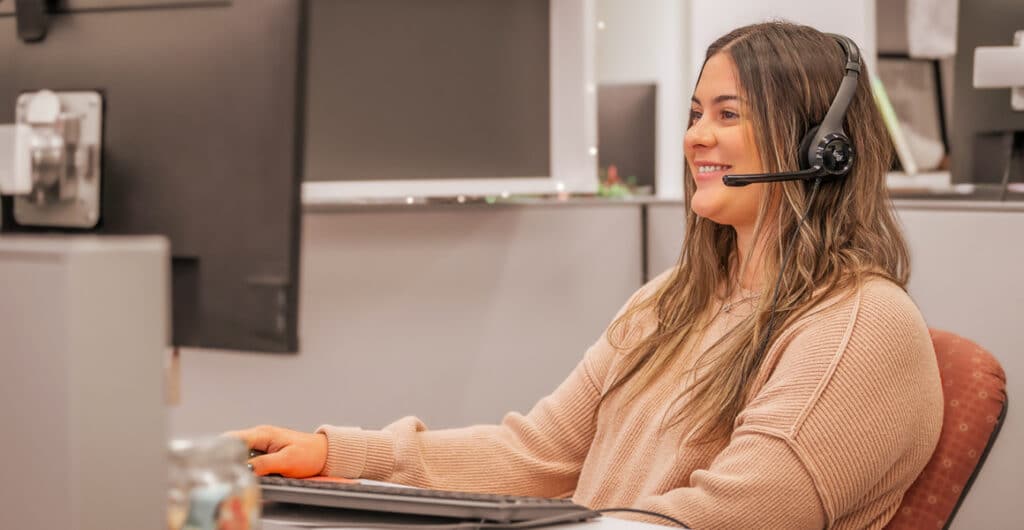 Smiling woman assisting someone virtually over a computer